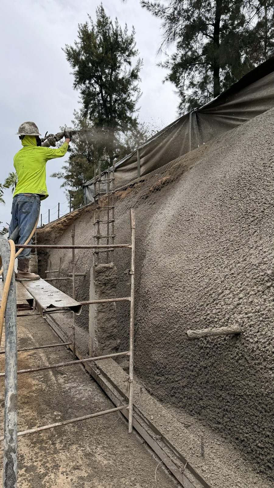 Concreto lanzado sobre malla, trabajado desde andamio